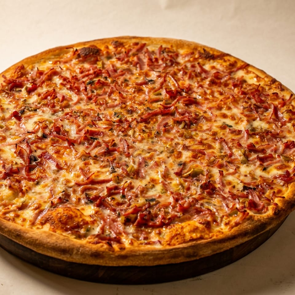 Thick-crust pizza topped with melted cheese, ham, and savory seasonings on a neutral surface.